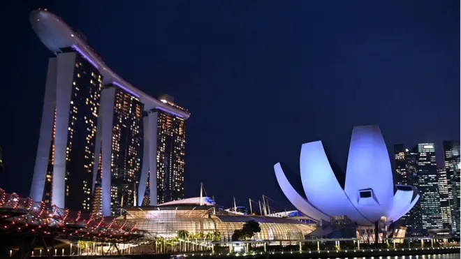 The Marina Bay Sands hotel and resorts (L) and the ArtScience Museum (R) are illuminated under the evening sky in Singapore on March 8, 2019