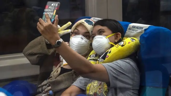 Penumpang kereta melakukan swafoto di sebuah stasiun di Surabaya.