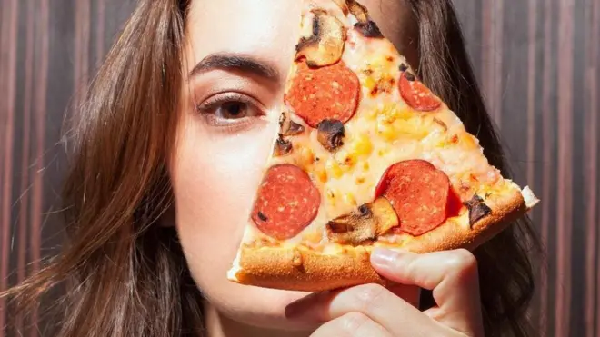فتاة تمسك بشريحة بيتزا