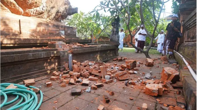 Pemuka agama Hindu memantau kerusakan pada bagian candi yang runtuh akibat gempa di Pura Lokanatha, Denpasar, Bali, Selasa (16/7).
