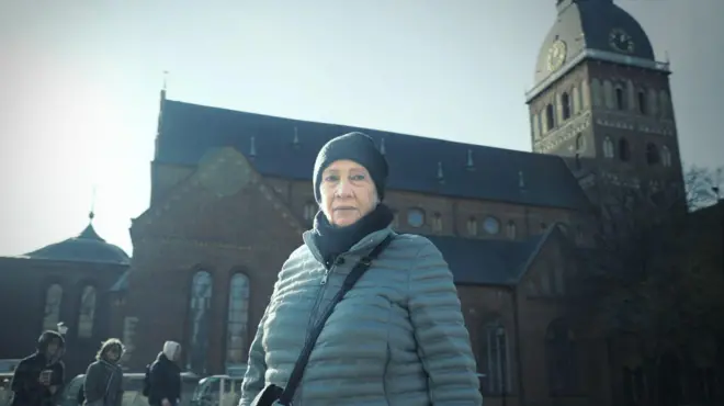 Галина Николаева, немолодая женщина в пальто и темной шапке, стоит на фоне Домского собора 