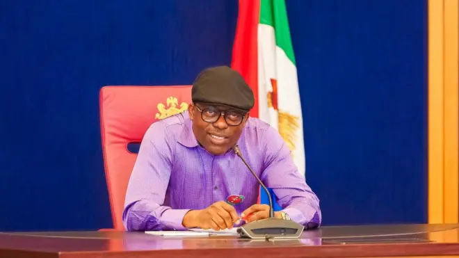 A man seated at a table - a mic is before him