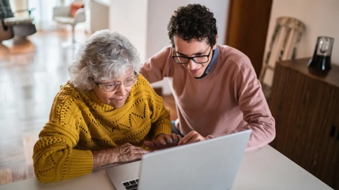 jovem mostrando algo no computador para idosa