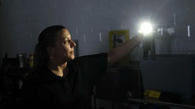 정전 속 핸드폰 플래시로 불을 비추고 있는 여성