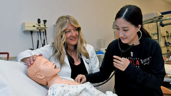 Dawn Mueller-Burke, left, a nurse practitioner and assistant professor at the University of Maryland School of Nursing, works with third-year student Anny Park, right, in the school's high-fidelity neonatal and pediatric simulation room on May 3, 2022. 