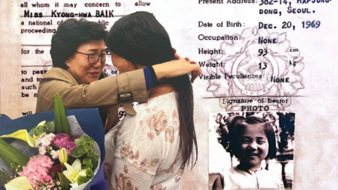 Mãe abraça filha com buquê de flores e cópia de documento ao fundo