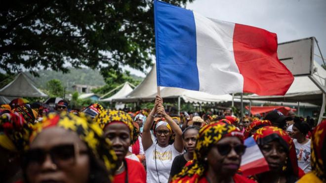 Una mujer ondea una bandera francesa durante una protesta contra las condiciones de vida y la inseguridad en la isla de Mayotte, el 14 de febrero de 2024.