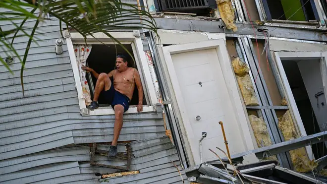 Un hombre en una ventana de una casa destrozada tras los sismos del miércoles 24 de junio en Venezuela