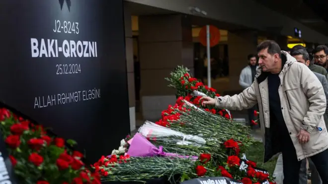 Люди кладуть квіти в пам’ять про жертв авіалайнера Embraer 190, який розбився біля казахстанського аеропорту Актау, у Міжнародному аеропорту імені Гейдара Алієва 26 грудня 2024 року в Баку, Азербайджан. . (Фото Азіза Карімова/Getty Images)