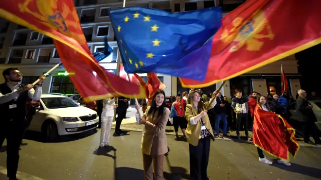 Devojka maše zastavom EU, oko nje zastave Crne Gore