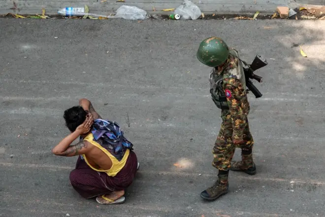  A soldier stands next to a detained man during a demonstration against the military coup in Mandalay on March 3, 2021.