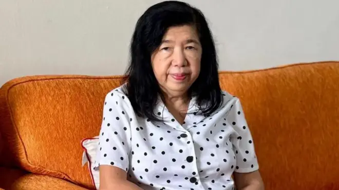 سوزانا لیو روی مبل زرد رنگی نشسته به دوربین نگاه می‌کند