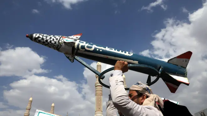 يمني مناصر لجماعة أنصار الله يرفع مجسماً لصاروخ "فلسطين-2" في العاصمة صنعاء