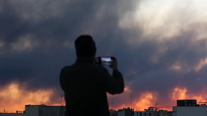 Muškarac slika dim iznad grada u suton