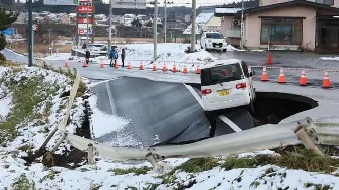 یک جاده که در اثر زلزله گودالی در آن ایجاد شده و خودرویی در حال سقوط در آن است
