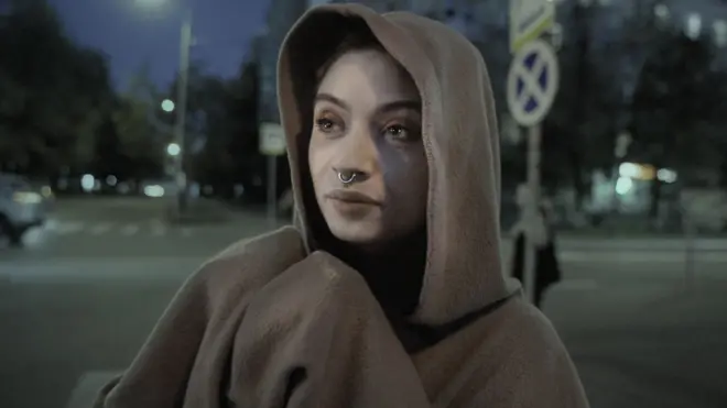 Бурнида ҳалга бор, бошига капюшон кийган ёш қиз