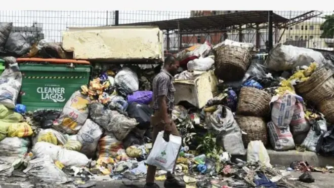 Aworan okete idọti ati ọkunrin kan to n kọja lọ niwaju rẹ.