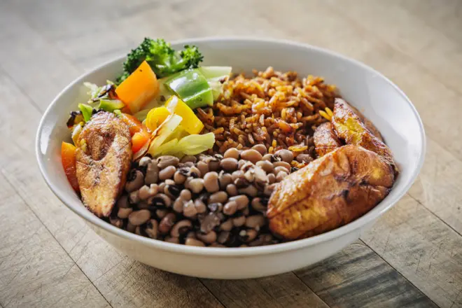 Bol de riz cuit à la tomate avec des haricots, de la banane plantain et des légumes