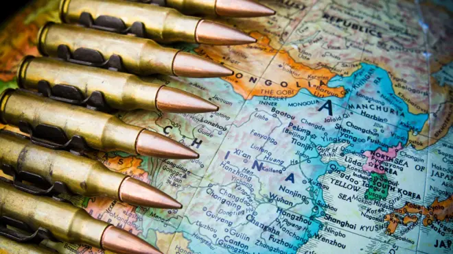 كرة أرضية مع التركيز على الصين وحزام ذخيرة رشاش ملفوف حولها.
