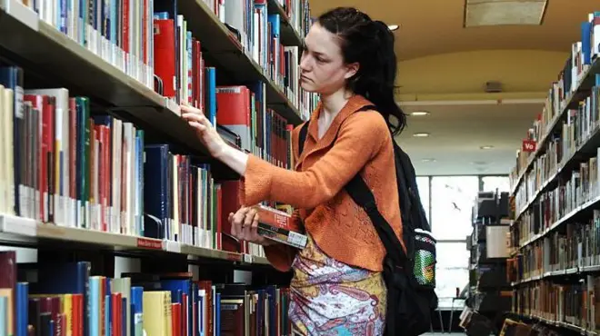 Mujer eligiiendo un libro en un biblioteca pública de Berlín, Alemania