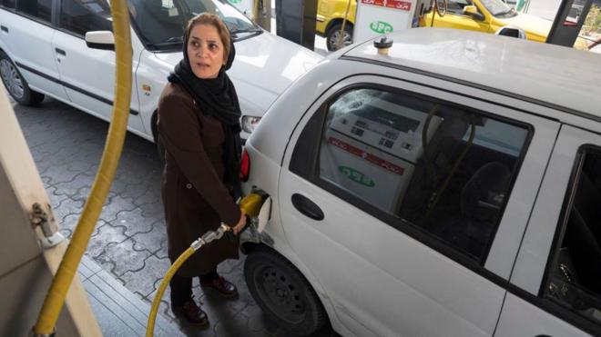 زنی در حال بنزین زدن در پمپ‌بنزینی در تهران