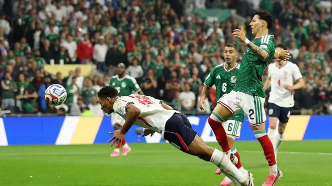 يظهر لاعب المنتخب الإنجليزي بلباس فريقه الأبيض والكحلي وهو يقفز باتجاه الكرة ليضربها برأسه وخلفه لاعبان من فريق المكسيك بلباس الفريق الأخضر والأبيض، يحاول أحدهما منعه من تسديد الكرة.