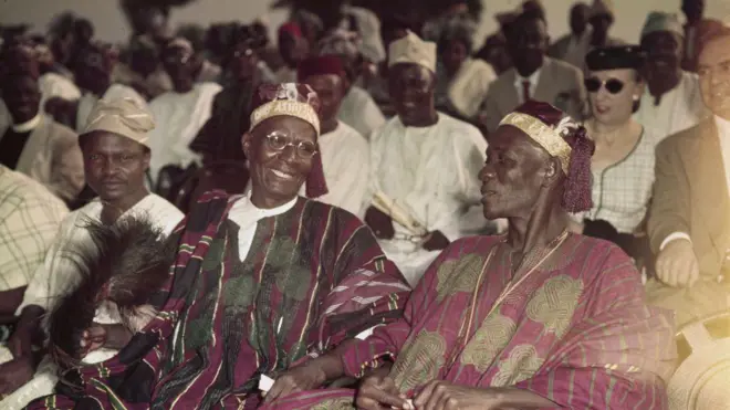 Aworan awon agbalagba okunrin meji ti won wo aṣo òfì, ati awon eeyan miran ti won wa nikalẹ nibi ipejọ agba kan