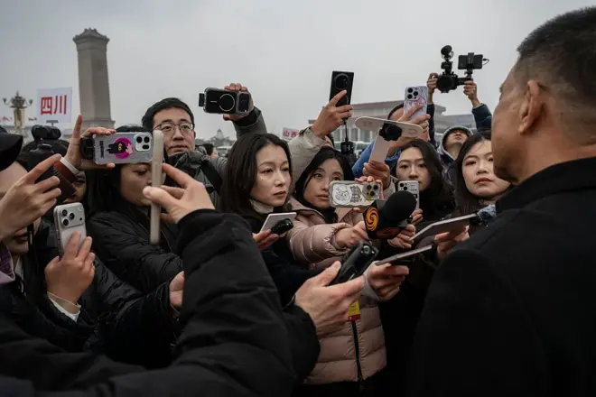 很多人拿着手机个话筒对准一个男性