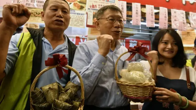 台北市长柯文哲（中）在一处传统市场和选民互动。台湾选举融入了浓郁的地方特色。