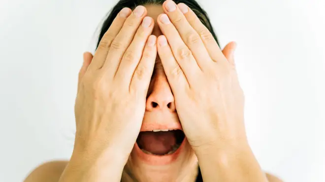 Жінка кричить, закривши обличчя руками - стокове фото