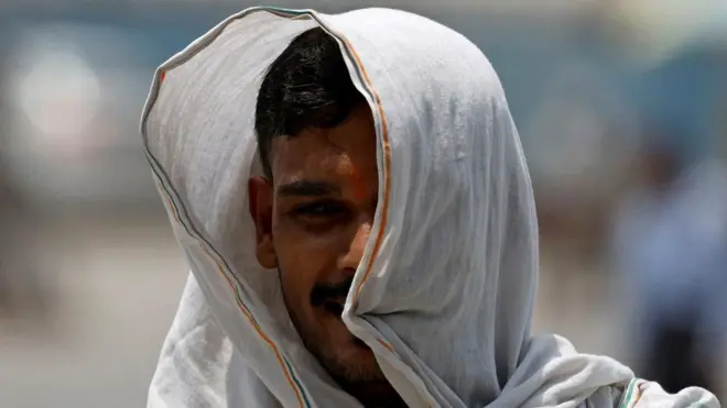 Un homme se couvre d'un tissu pour se protéger de la chaleur lors d'une chaude journée d'été à New Delhi, en Inde, le 20 mai 2024. 
