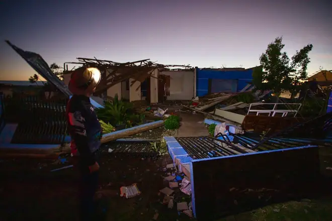 Casas destruídas e um homem olhando para destruição