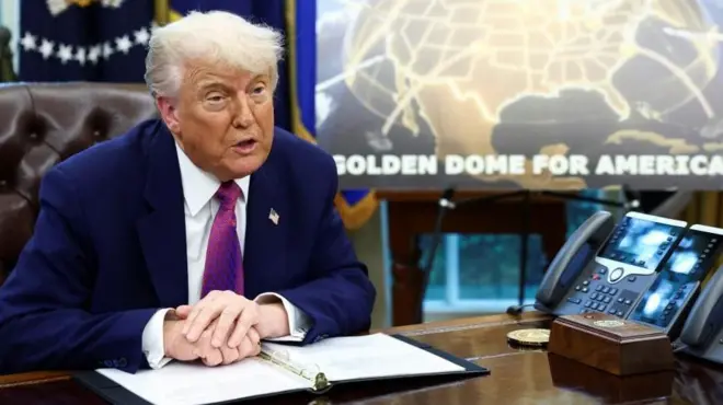 Donald Trump in the Oval Office in front of a Golden Dome poster