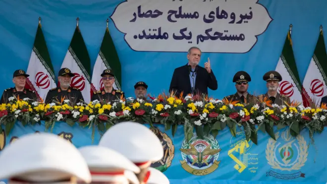 الرئيس الإيراني مسعود بزشكيان (وسط) يتحدث أثناء وقوفه بجانب قادة الجيش الإيراني والحرس الثوري الإسلامي خلال عرض عسكري لإحياء ذكرى الحرب الإيرانية العراقية (1980-1988) خارج ضريح الخميني في جنوب طهران، إيران، في 21 سبتمبر 2024.
