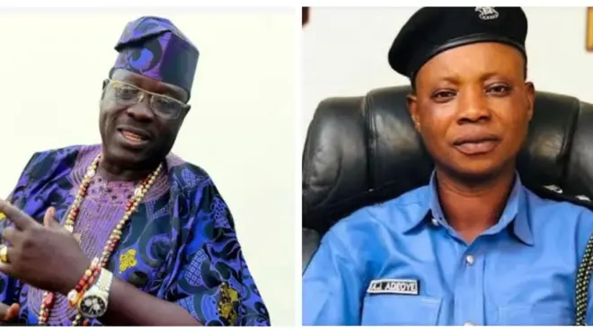 Taiwo Hassan Ogogo wọ Damaasi alawọ aro, o de fila, o lo ilẹkẹ sọrun o si fi aago sọwọ pẹlu ilẹkẹ. Owolabi Ajasa lo wa lapa ọtun, o wọsọ ọlọpaa alawọ aro o si de fila dudu