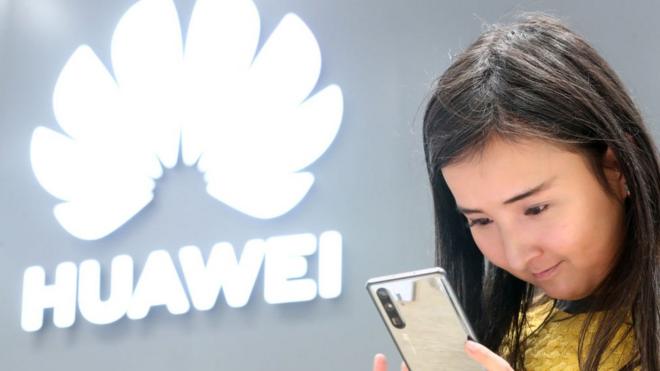 Una mujer joven mirando un teléfono inteligente Huawei.