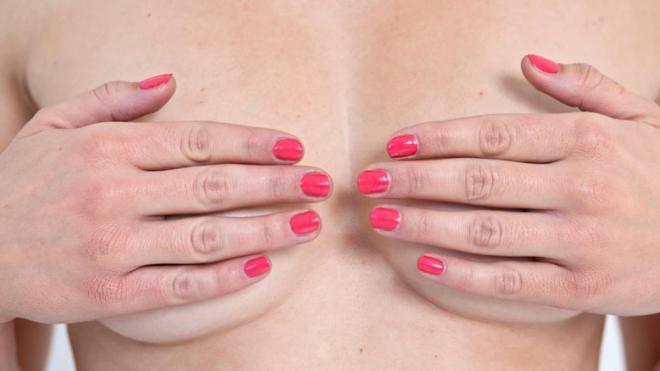 Женщина закрывает ладонями грудь