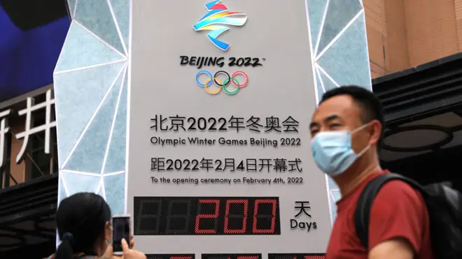 A woman uses her phone in front of a countdown clock showing 200 days to the opening of Beijing 2022 Winter Olympic Games, in Beijing, China July 19, 2021.