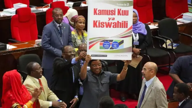 Waziri Mkuu wa Tanzania , Kassim Majaliwa akionyesha Kamumusi Kuu ya Kiswahili baada ya kuizindua kwenye ukumbi wa Bunge mjini Dodoma Juni 19, 2017. Kulia ni Mwenyekiti wa Bunge na Mbunge wa Ilala, Mussa Azan Zungu. Kushoto ni Balozi wa Kiswahili Afrika, Mama Salma Kikwete. Wapili kushoto ni Waziri wa Habari, Utamaduni, Sanaa na Michezo, Dkt. Harrison Mwakyembe