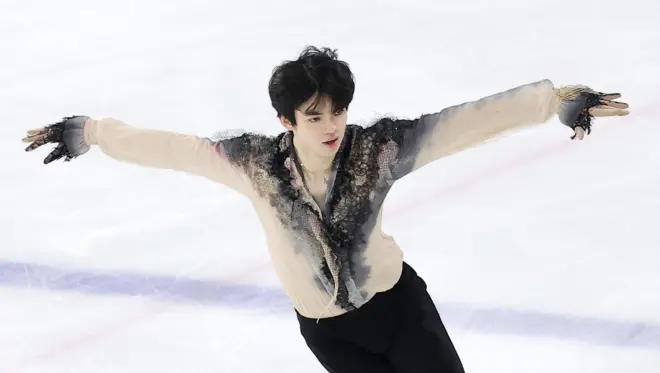 밝은 살구색의 상의와 검정 하의 피겨스케이팅 복장을 한 차준환 선수가 얼음 위에서 팔을 펼치고 연기를 선보이고 있다 