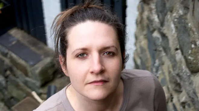 Ruth has dark hair and is looking directly at the camera.