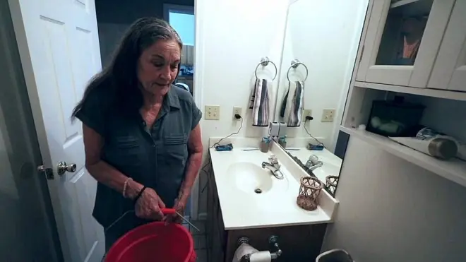 Bevery Morris en el baño de su casa con un balde