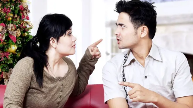 Una pareja discutiendo frente a un árbol de Navidad