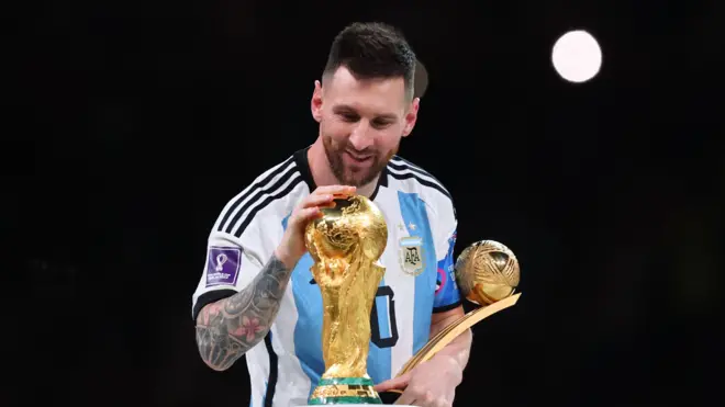 ليونيل ميسي يحمل جائزة أفضل لاعب في مونديال 2022، ويضع يده على كأس العالم