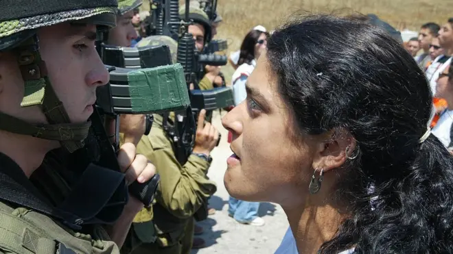 इसराइली सैनिक के सामने फ़लस्तीनी प्रदर्शनकारी