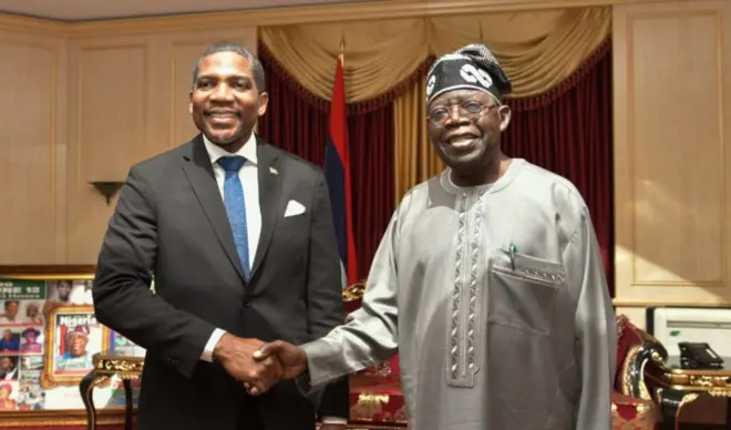 St. Kitts and Nevile Prime Minister Terrance Drew wey wear black suit and blue tie shake hands wit Nigeria President Bola Tinubu wey appear for one light brown traditional attire