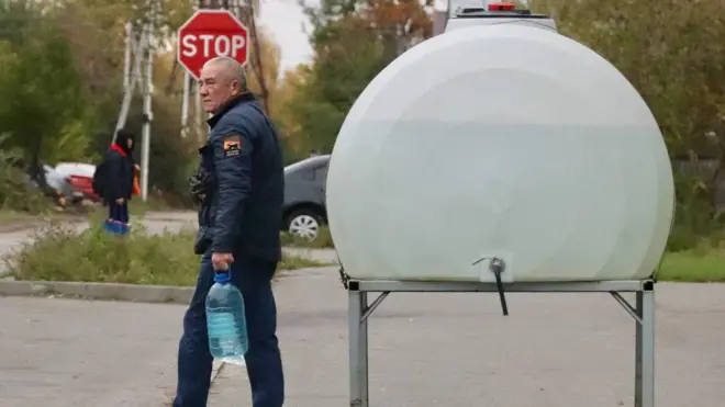 Чернігів, чоловік у синій куртці з бутлем води йде біля каністри з водою