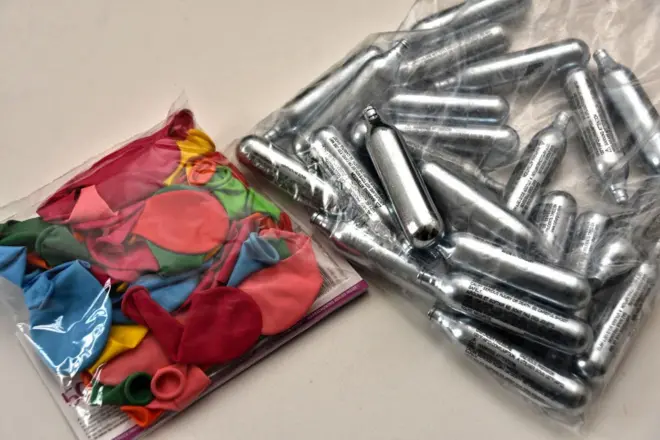 Foto mostra um pacote de balões e um de cilindros pequenos