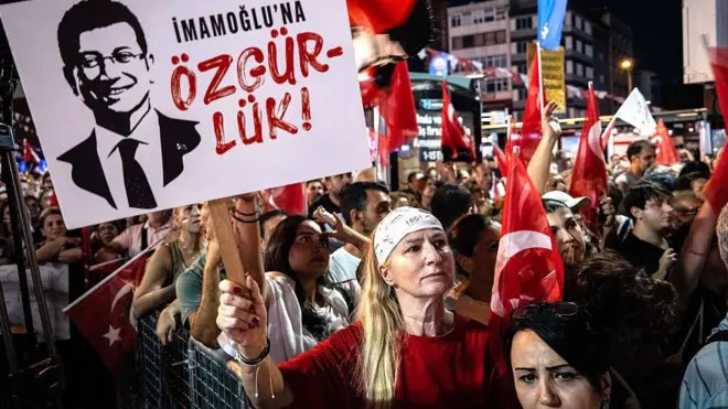 İstanbul'da İmamoğlu protestolarına katılan kalabalık bir kitle önünde bir kadın İmamoğlu'na özgürlük yazılı bir poster tutuyor