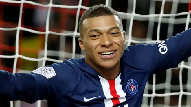 Kylian Mbappe, in close-up, turning and smiling to celebrate a goal